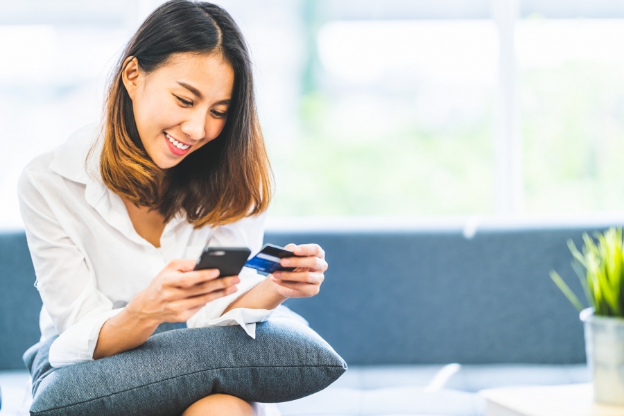 Pay with credit card Woman using her phone to pay online with her credit card