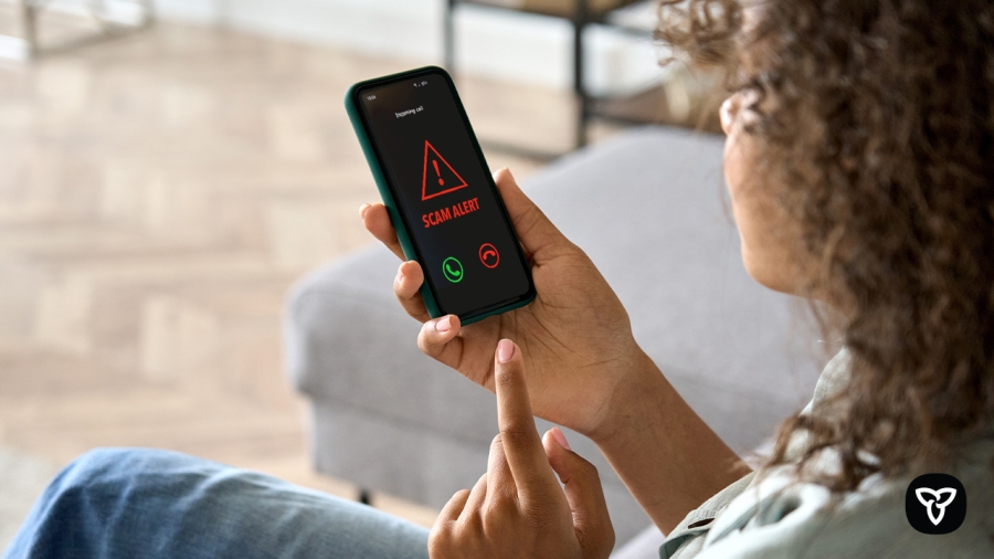 Woman holding a smartphone with a scam alert message showing