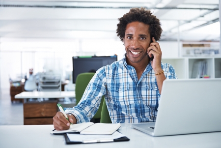 Working at the office Man sitting in front of laptop talking on the phone