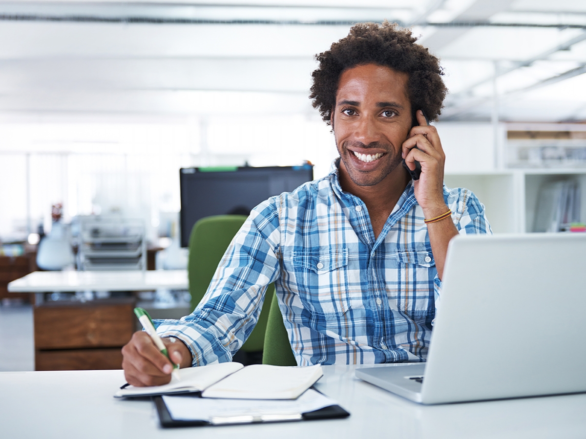 Working at the office Man sitting in front of laptop talking on the phone