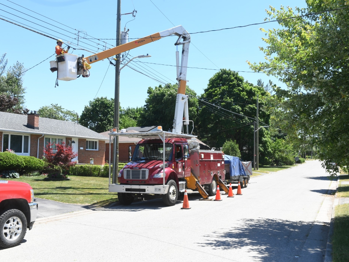 Linesmen service an overhead powerline in the bucket of a boom truck.