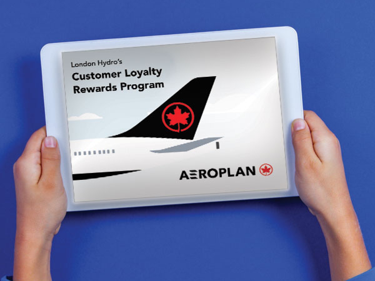 Hands holding an iPad showing the back end of an airplane promoting Aeroplan