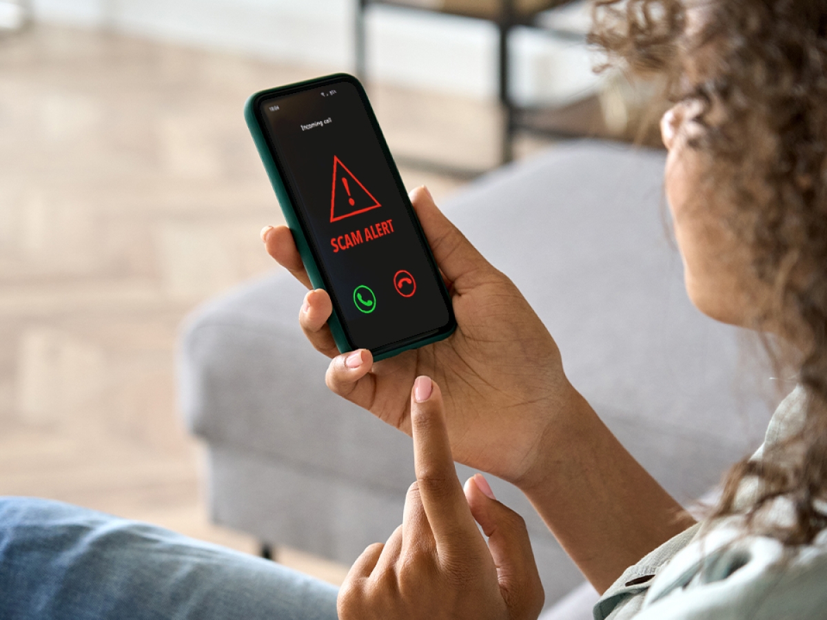 Scam Alert Woman holding a smartphone with a scam alert message showing