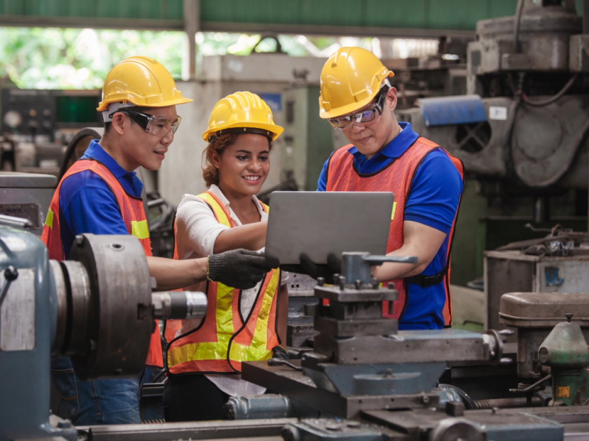 a crew win high vis looking at a computer in a factory
