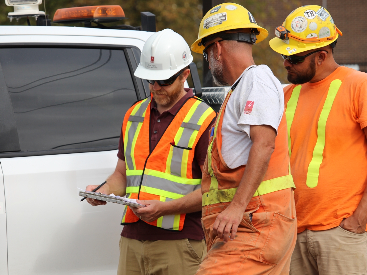 Three men standing by a truck going over paperwork