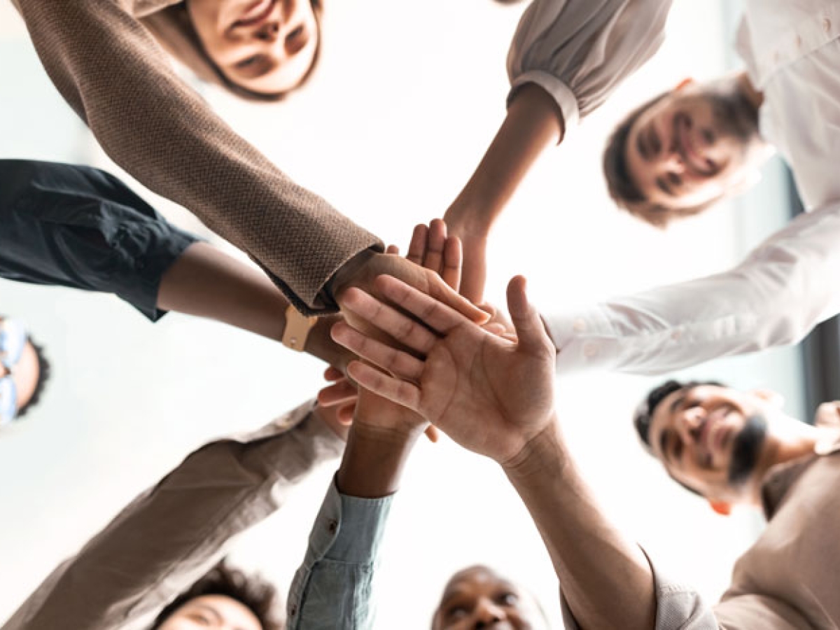 People placing their hands on top of other hands in a team building way