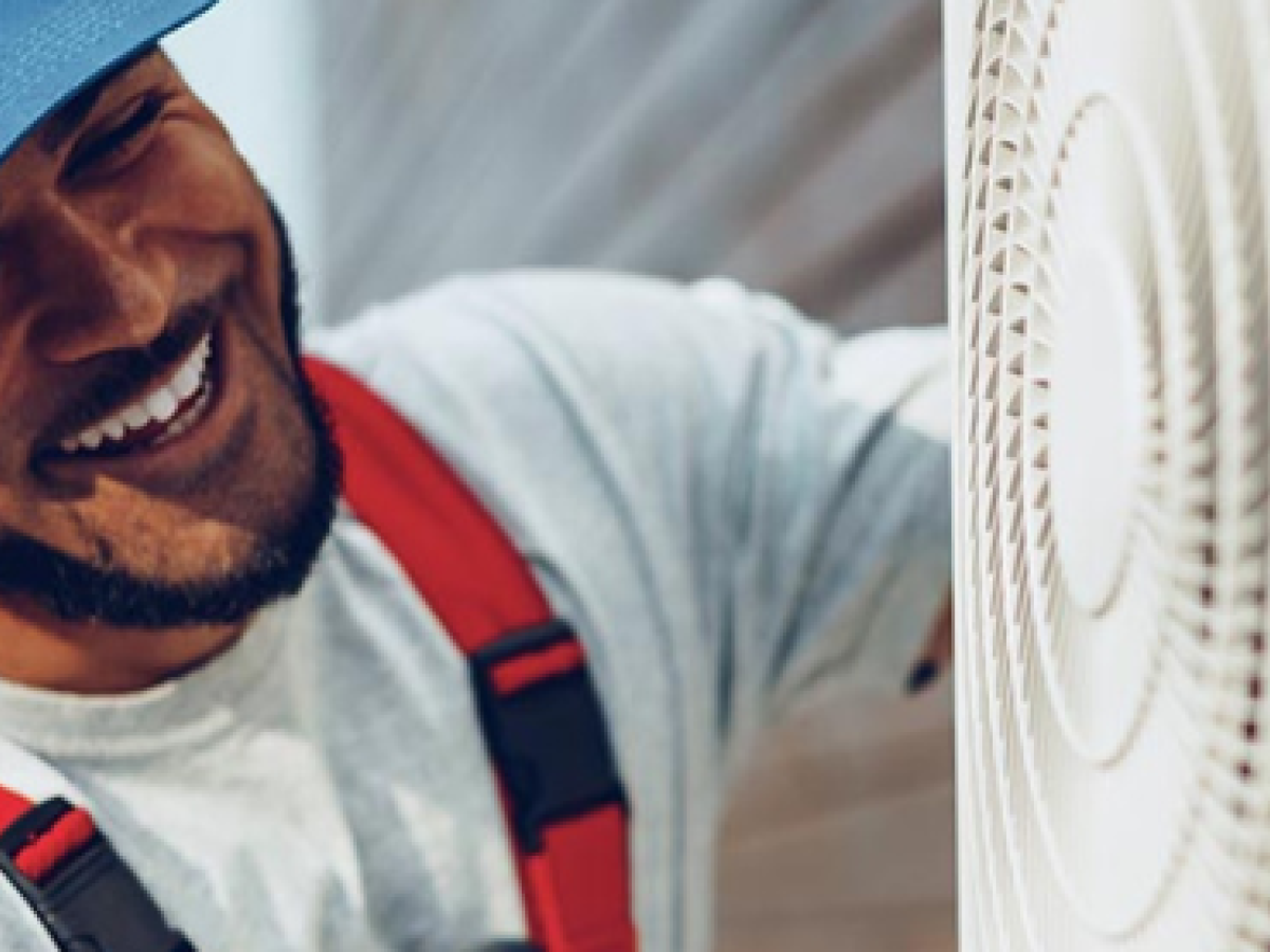 A man smiling as he fixes a heat pump