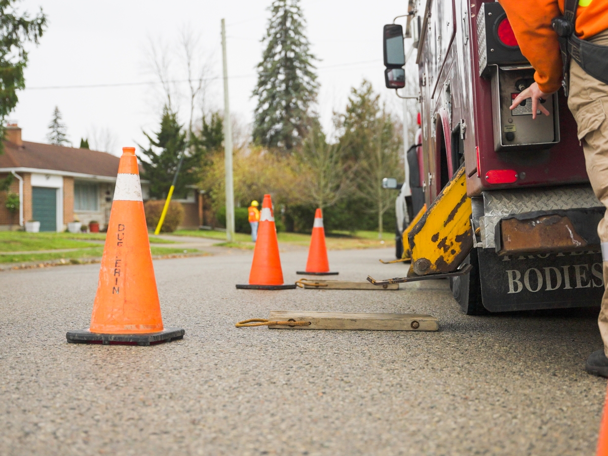 Orange pylons blocking hydro truck that is parked on the side of the road